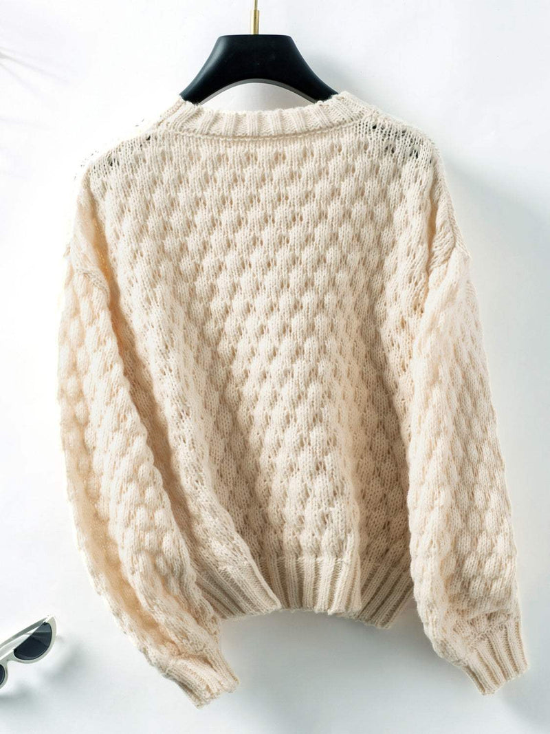 Cable-knit round neck long sleeve sweater in cream color.