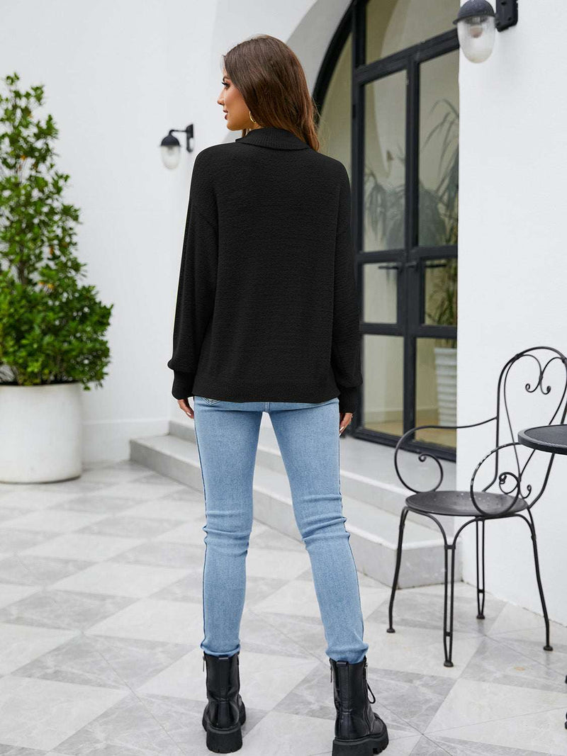 Turtleneck dropped shoulder sweater in black, paired with blue jeans.