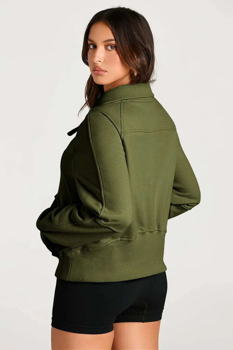 Woman wearing a green Half Zip Long Sleeve Sweatshirt with black shorts.