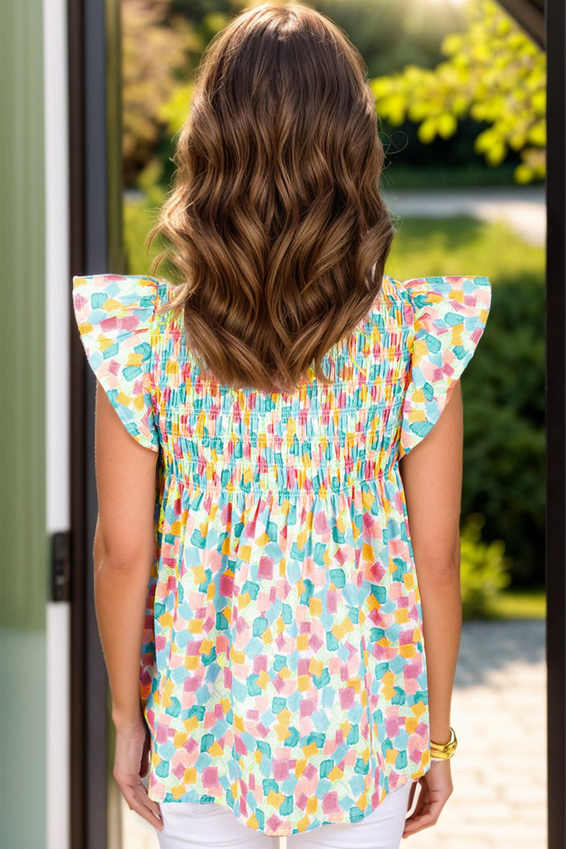 Ruffled printed notched cap sleeve blouse in multicolor pattern, polyester material, worn by model outdoors.