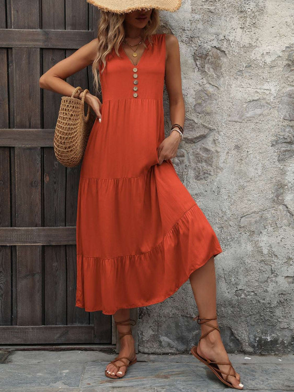 Ivy Lane Decorative Button Notched Sleeveless Dress in orange, featuring a notched neckline and tiered design, worn with a straw hat and sandals.