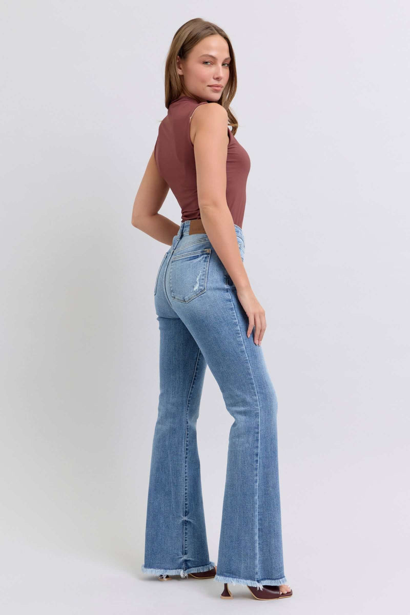 Woman wearing Judy Blue Full Size Raw Hem High Rise Bootcut Jeans, showcasing trendy and stylish denim with raw hem and high-rise fit.