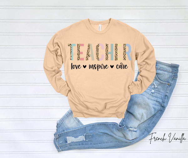 Teacher Love Sweatshirt with "Teacher, love, inspire, care" text design on beige background.