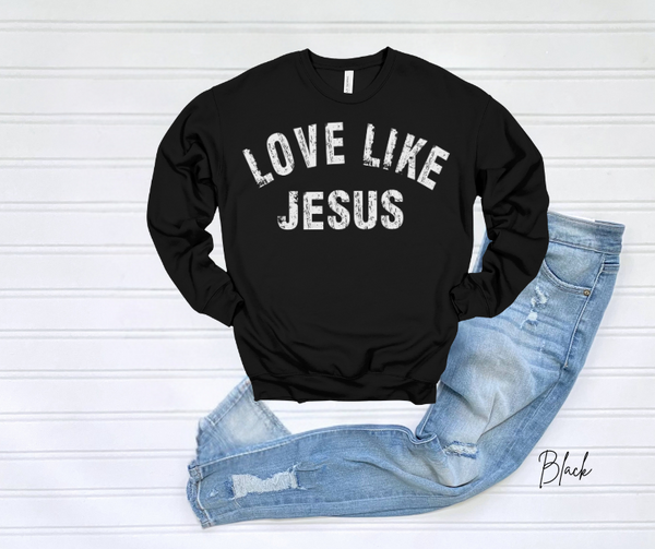 Black "Love Like Jesus" sweatshirt on display with ripped jeans.