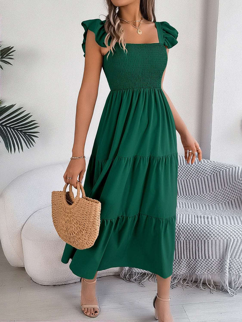 Smocked square neck cap sleeve midi dress in green with tiered skirt, styled with woven handbag.