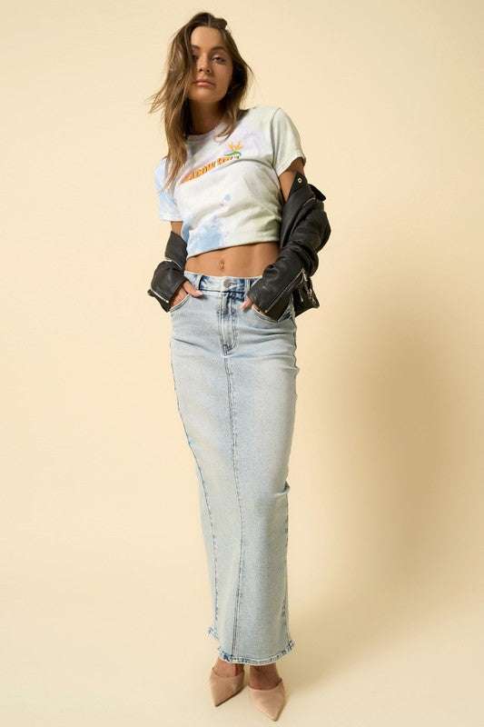 Woman wearing light wash denim super long maxi skirt with front zipper fly and t-shirt.