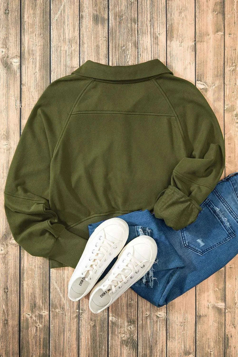 Half Zip Long Sleeve Sweatshirt in olive green paired with jeans and white sneakers on wooden background.