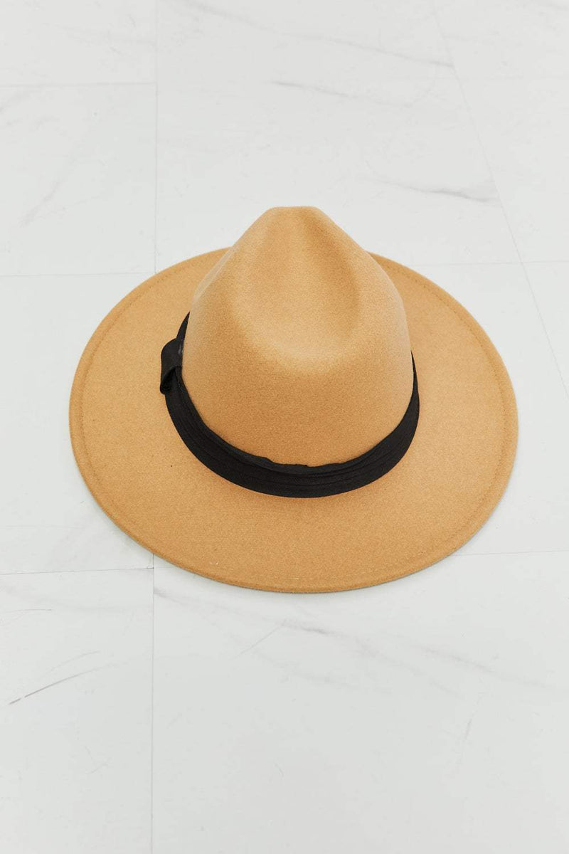 Dark tan fedora hat with black ribbon detail on a white background.