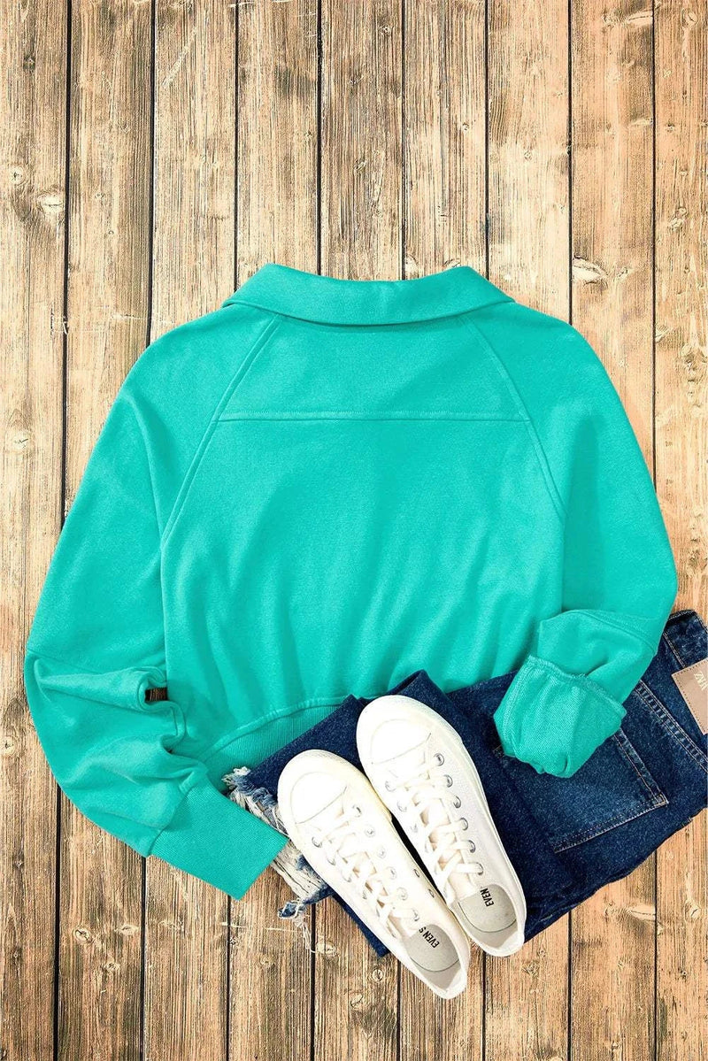 Half Zip Long Sleeve Sweatshirt in teal with white sneakers and blue jeans on a wooden floor.