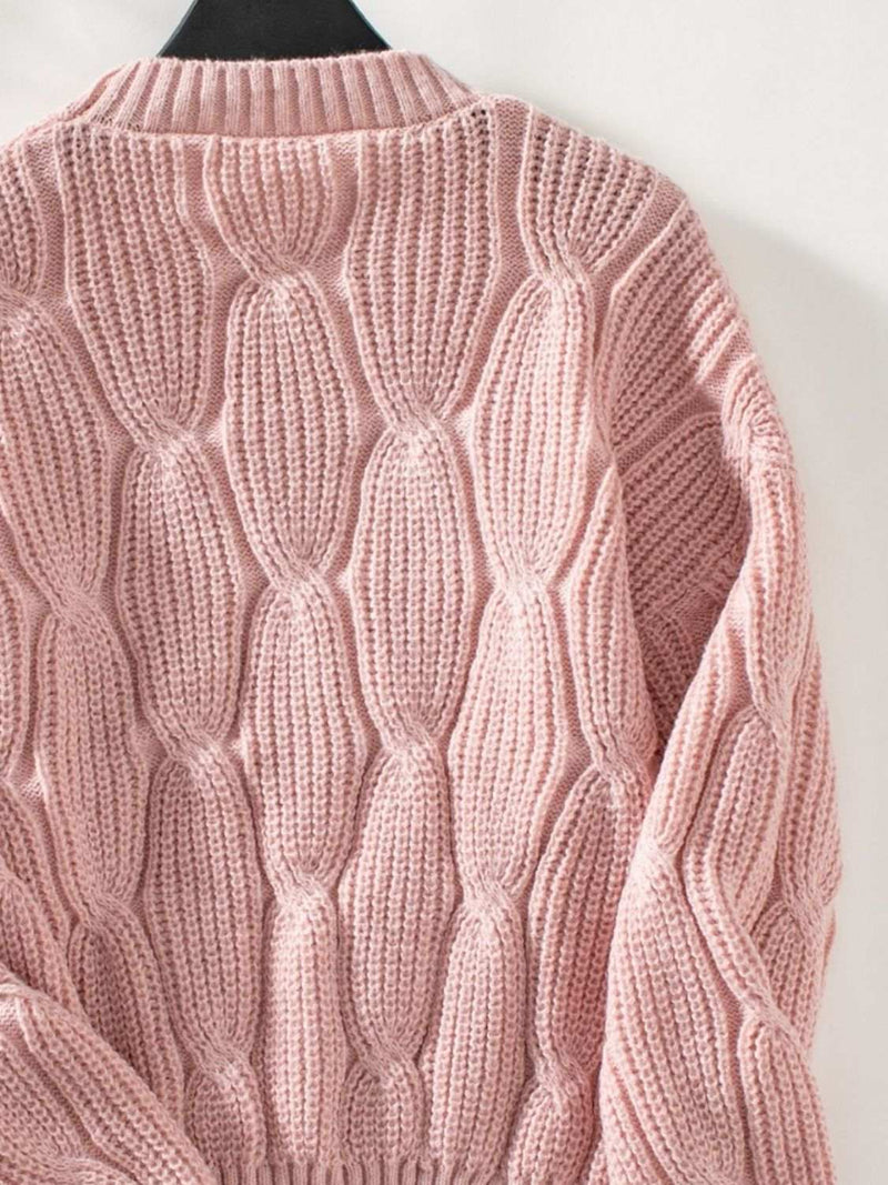 Pink round neck dropped shoulder sweater with textured knit design.