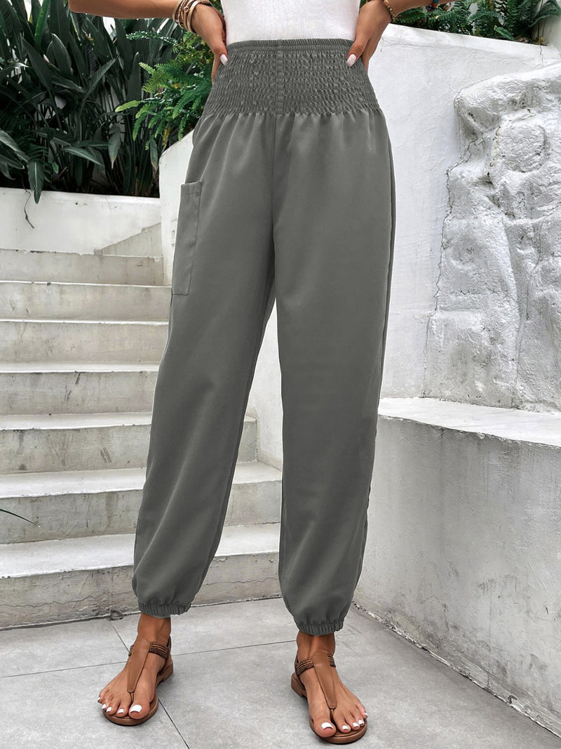 Smocked high rise joggers with pockets in gray, basic style, worn by a woman on stairs.