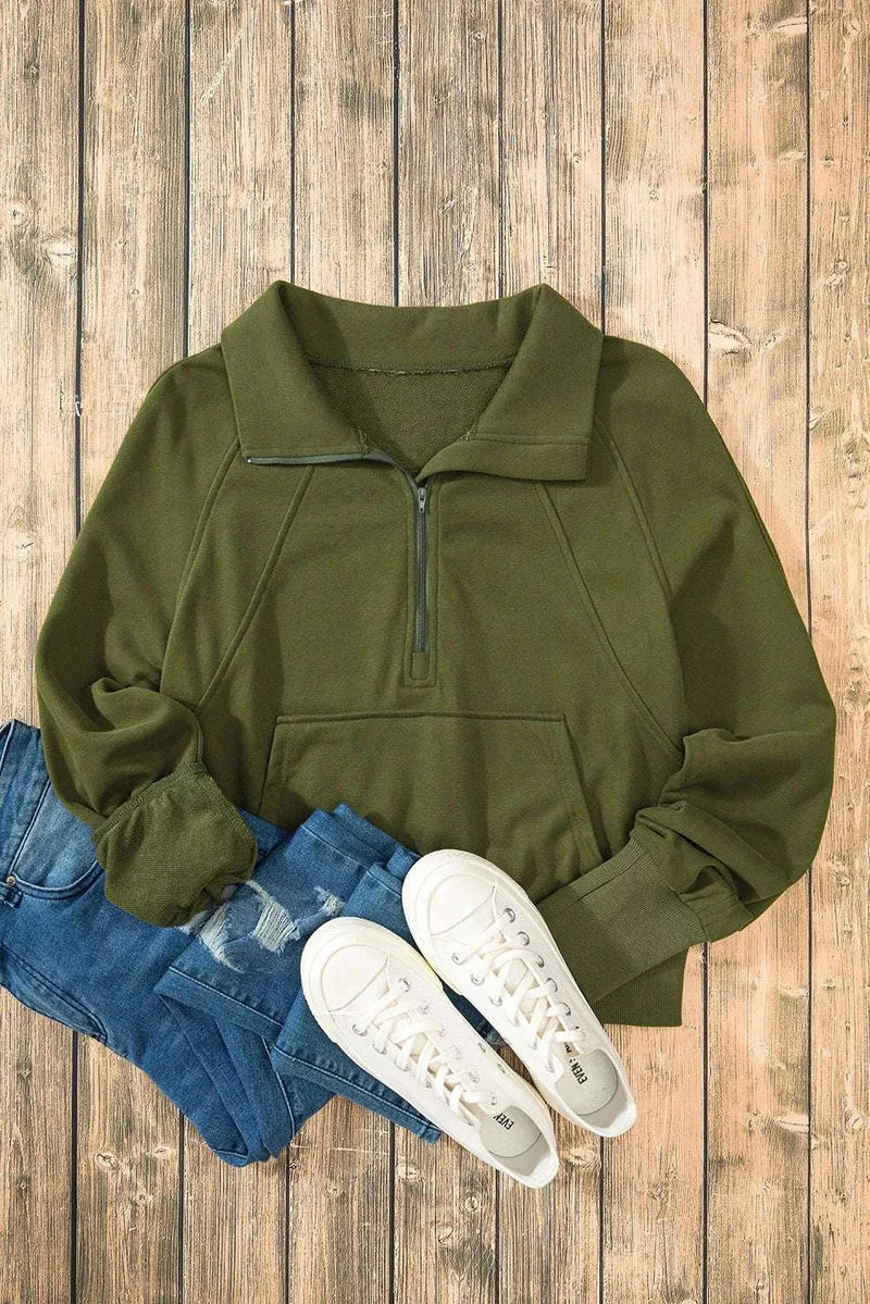 Olive green half zip long sleeve sweatshirt on wooden background with jeans and white sneakers.