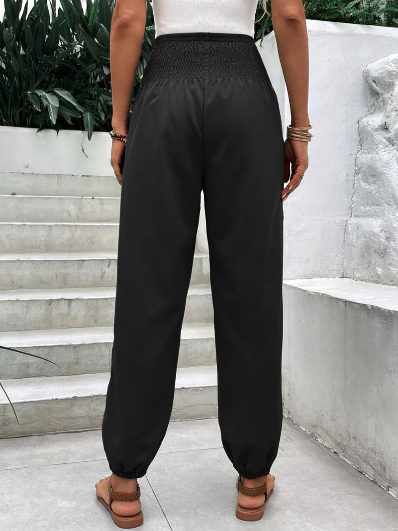 Smocked high rise joggers with pockets in black fabric, back view.