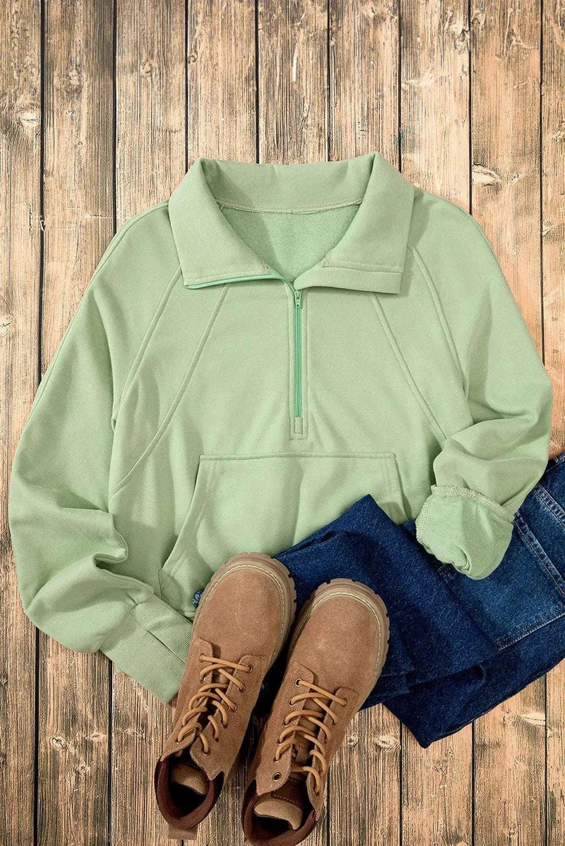 Half Zip Long Sleeve Sweatshirt in green with jeans and boots on a wooden background.