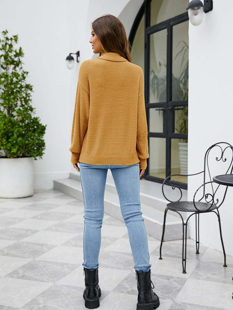 Turtleneck dropped shoulder sweater in mustard, styled with jeans and black boots.