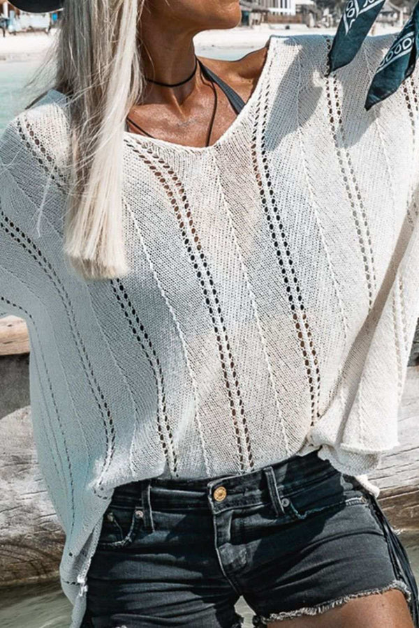 Openwork V-neck long sleeve knit top in white, featuring slightly stretchy material, worn outdoors.