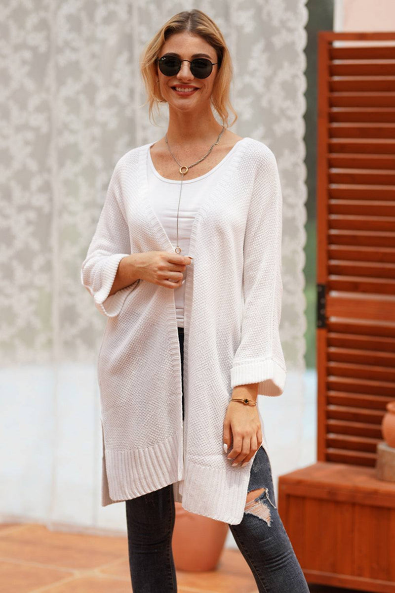 Open front long sleeve cardigan in white, slightly stretchy acrylic material, worn by a woman.