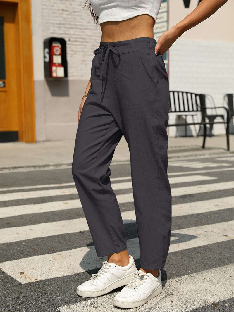 Elastic waist tapered pants in cotton and linen blend, worn outdoors.