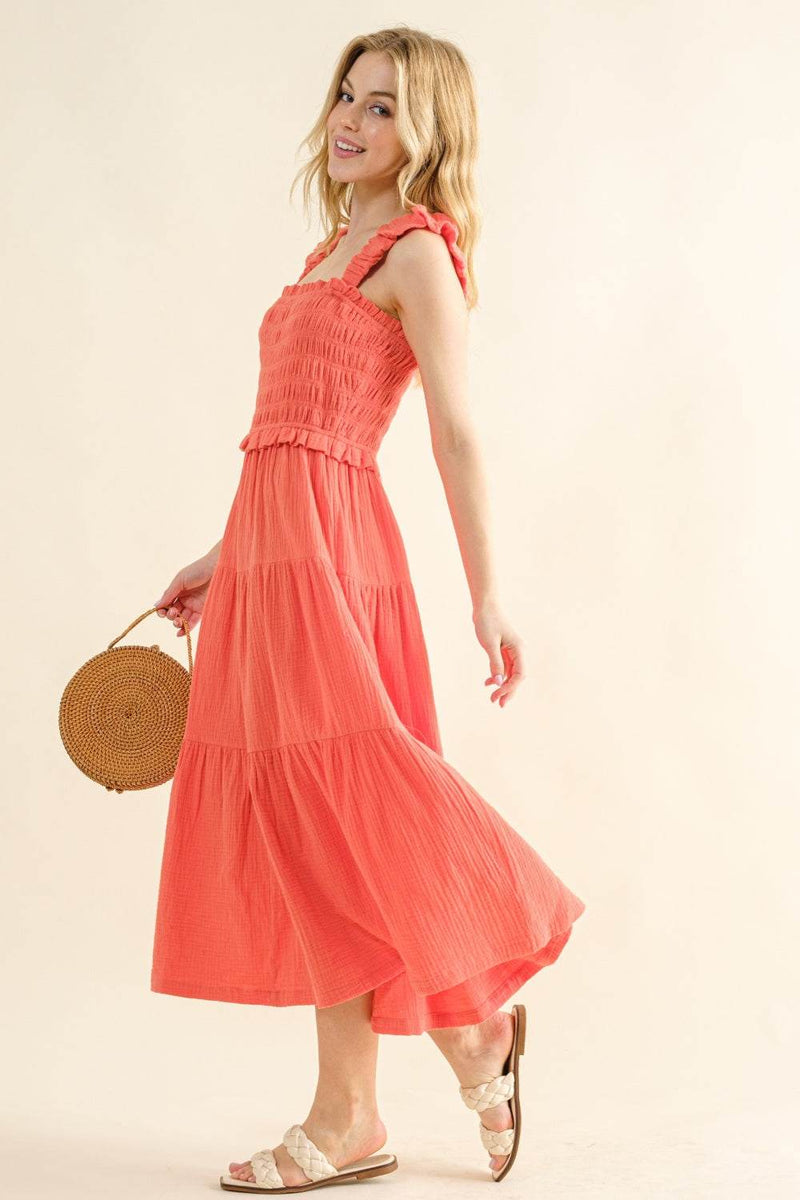 Smocked Ruffled Tiered Dress in coral, worn with sandals and a wicker handbag.