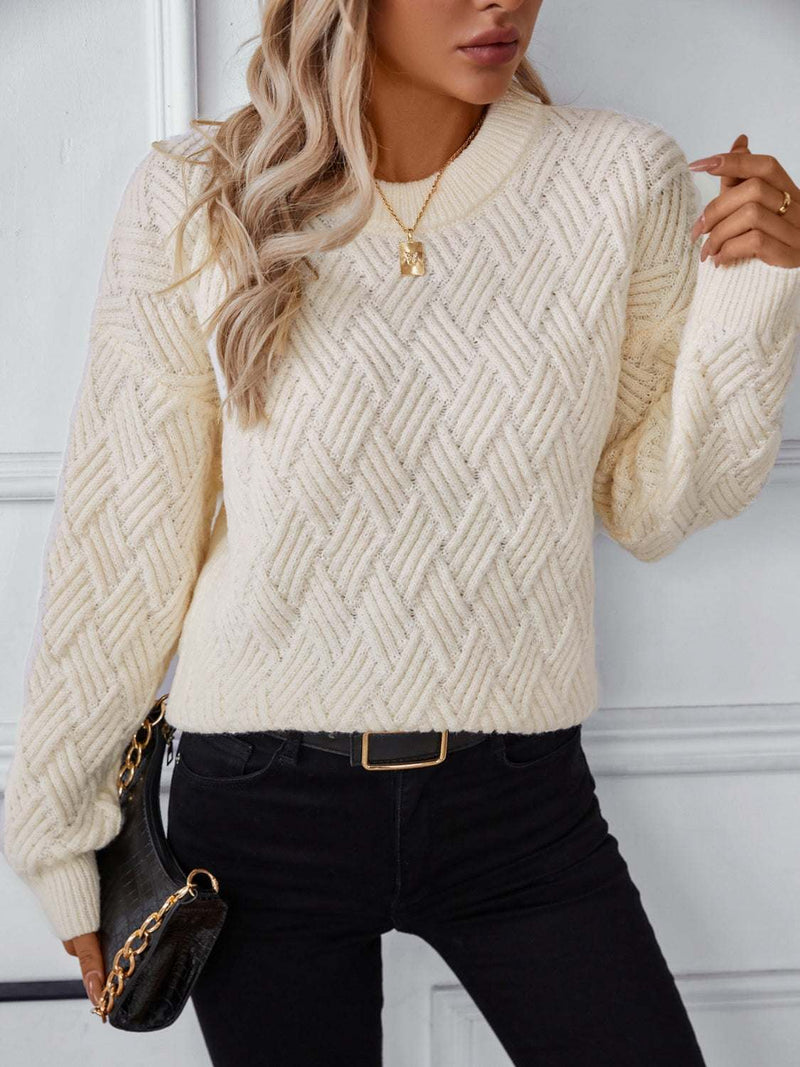 Round Neck Long Sleeve Woven Sweater in cream, featuring a textured pattern, worn with black jeans and a black handbag.