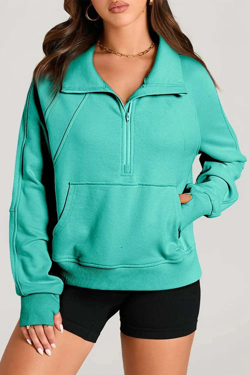 Woman wearing green half zip long sleeve sweatshirt with black shorts.