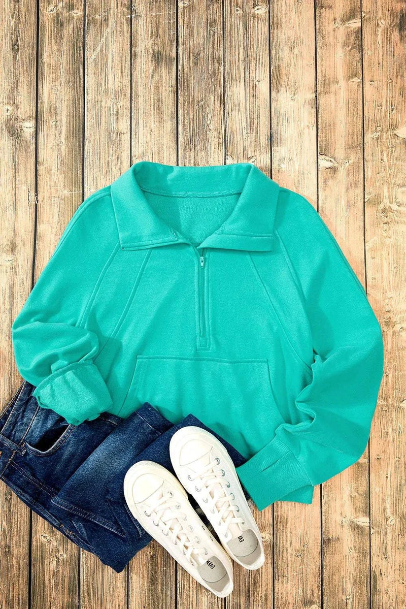 Half Zip Long Sleeve Sweatshirt in teal, laid out with jeans and white sneakers on a wooden background.