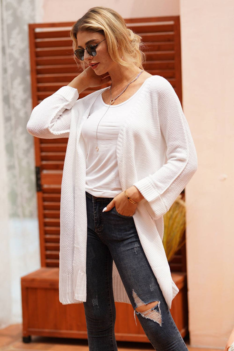 Woman wearing an open front long sleeve white cardigan.