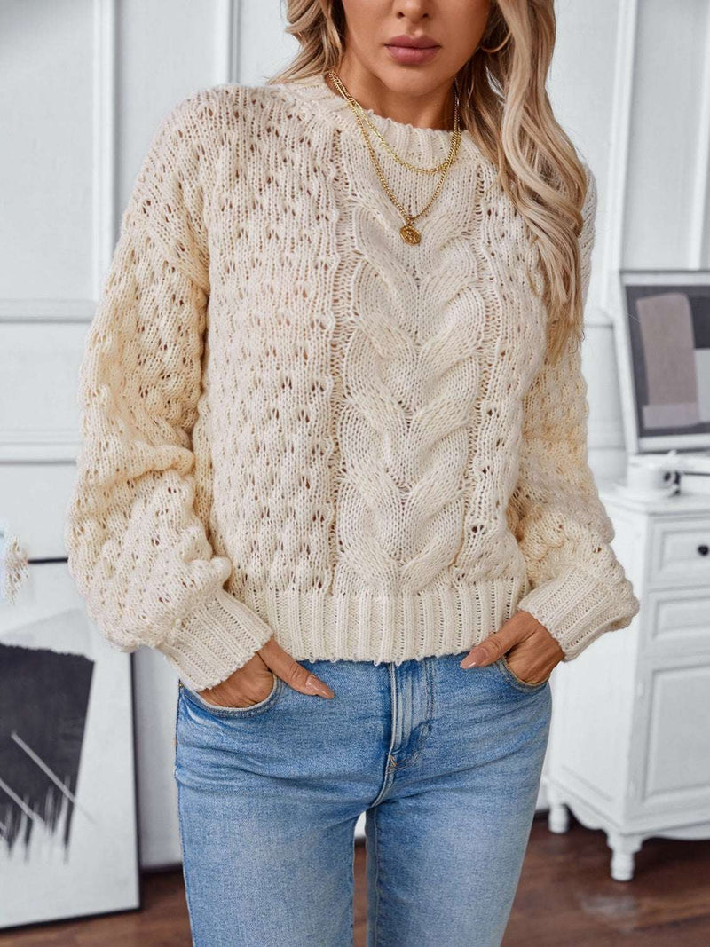 Cable-knit round neck long sleeve sweater in cream color, styled with jeans.