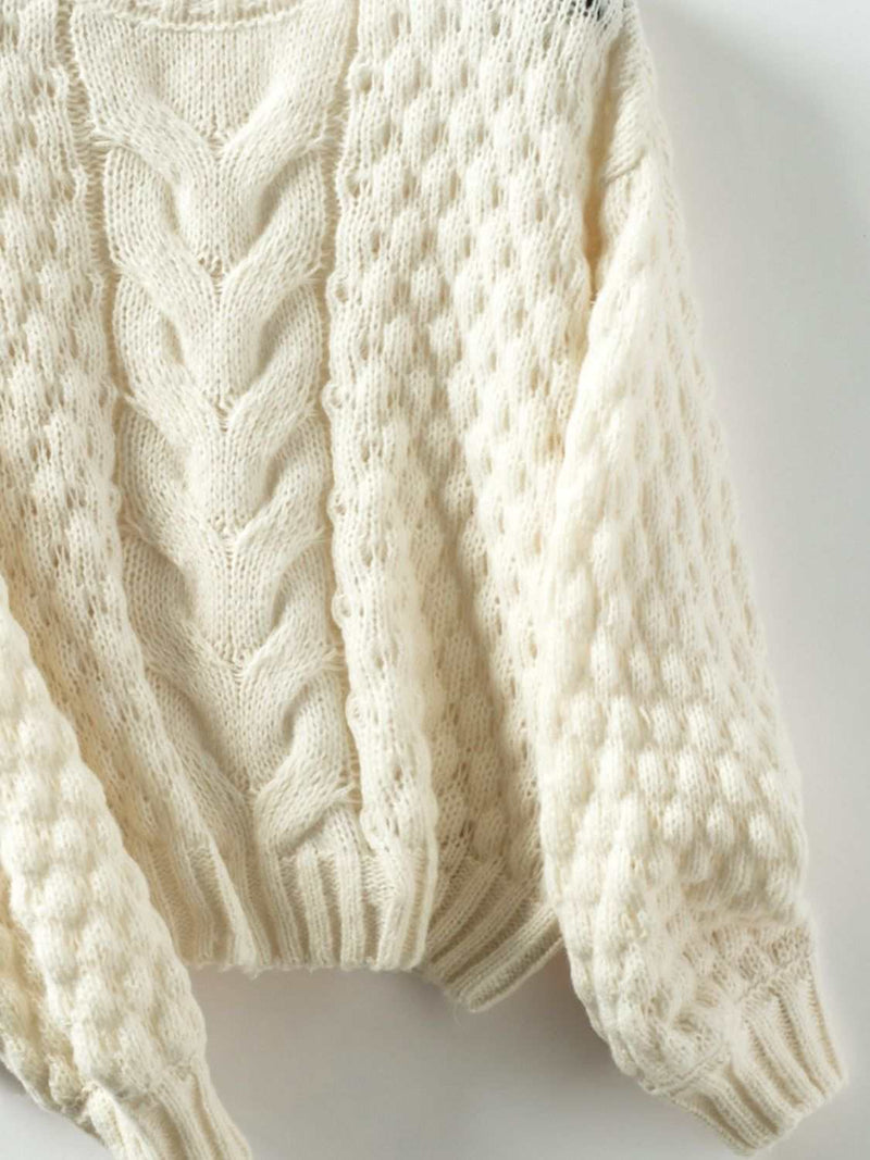 Cable-knit round neck long sleeve sweater in cream color.