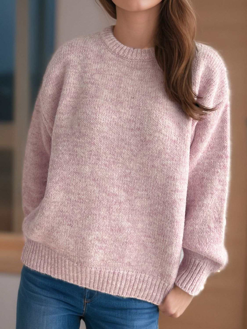 Round neck long sleeve sweater in soft pink, worn by a person for a casual and cozy look.