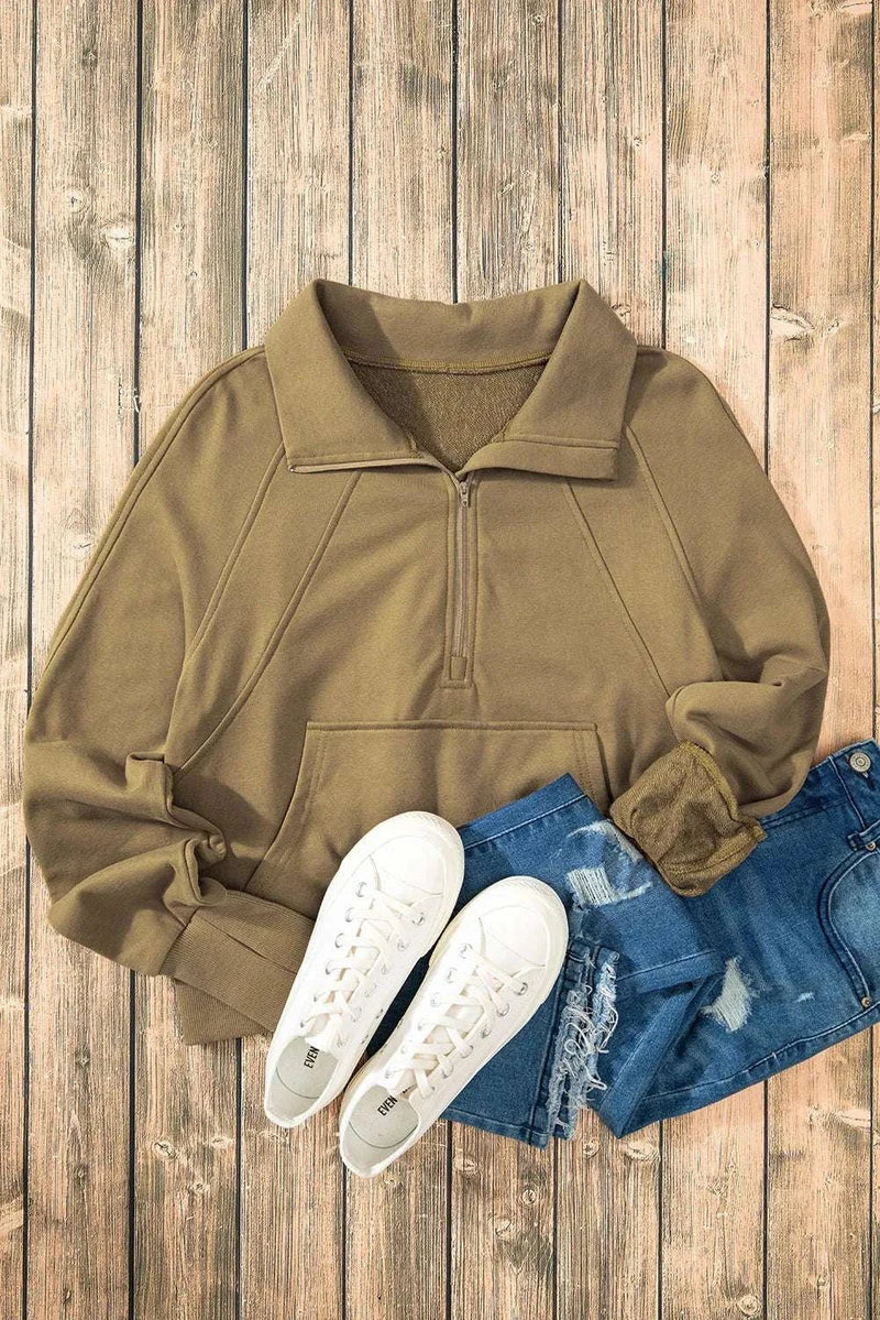 Half zip long sleeve sweatshirt in brown on wooden background with white sneakers and blue jeans.