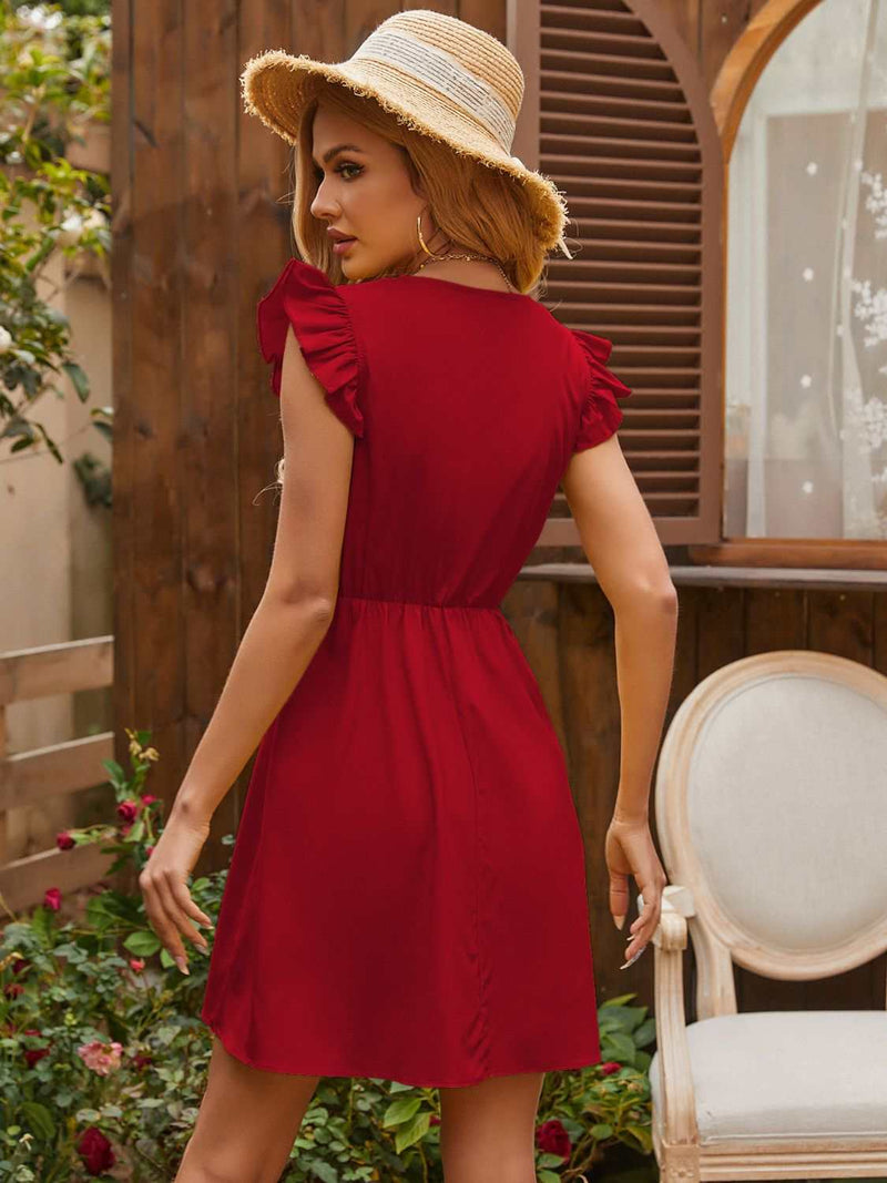 Red ruffled V-neck cap sleeve mini dress in garden setting.