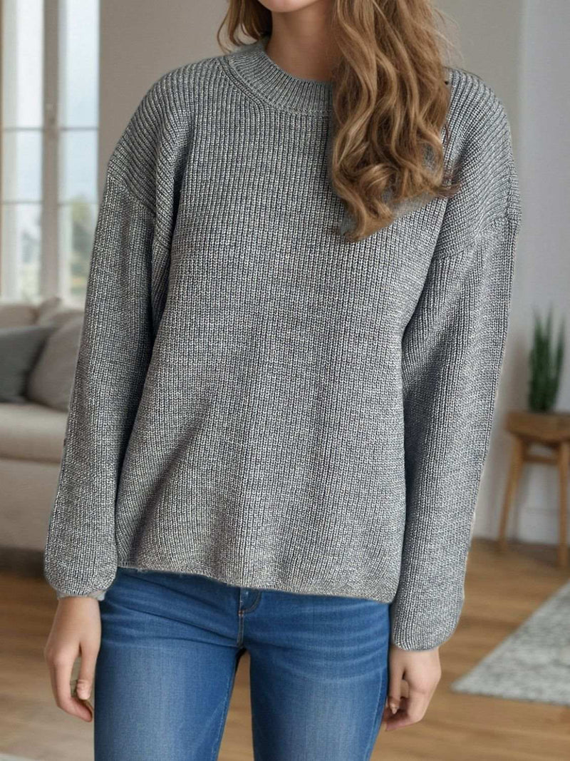 Solid color round neck long sleeve sweater in grey, slightly stretchy, worn by a model indoors.