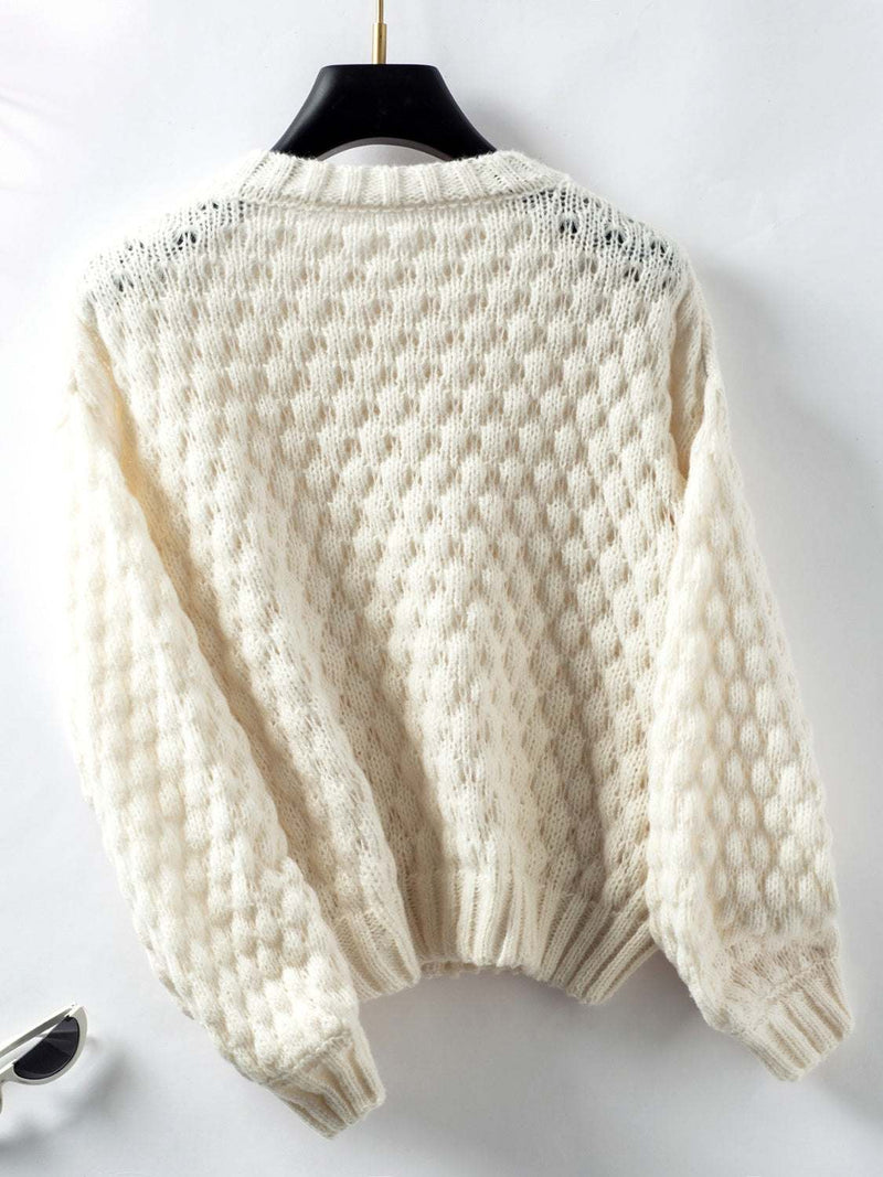 Cable-knit round neck long sleeve sweater in a cozy, textured design on a hanger.